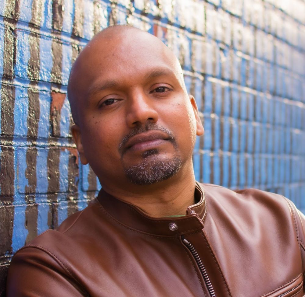 Color photo portrait of Zaheer Ali wearing a light brown leather coat.